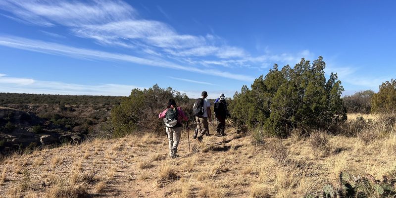 Hikers with daypacks on a backcountry trail along the canyon rim