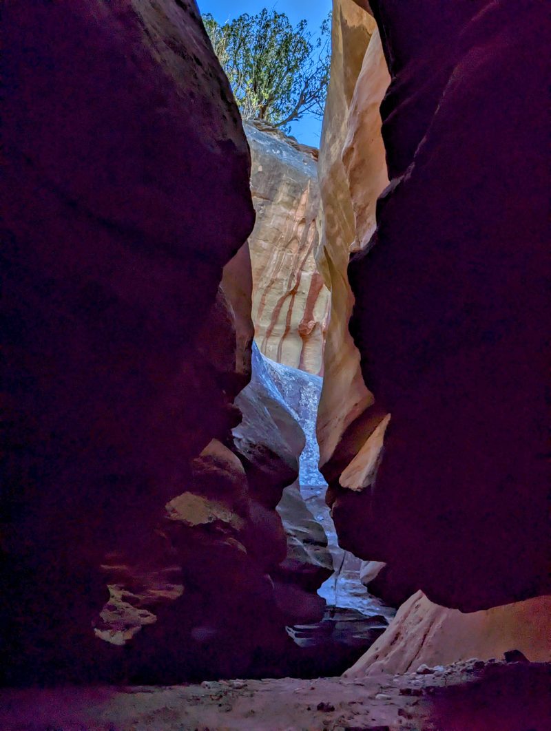 Dark red walls of a narrow slot canyon opening to a sliver of sky