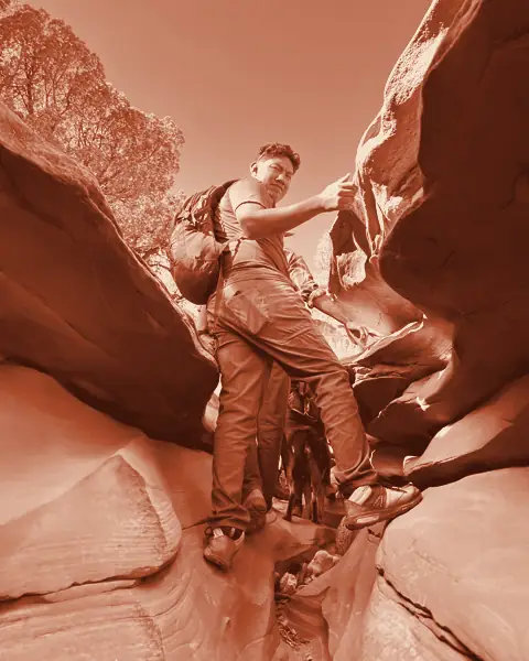 Hiker with a daypack scrambling up sandstone
